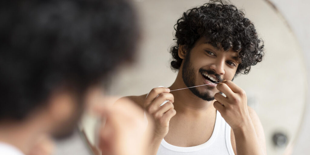 man flossing in mirror