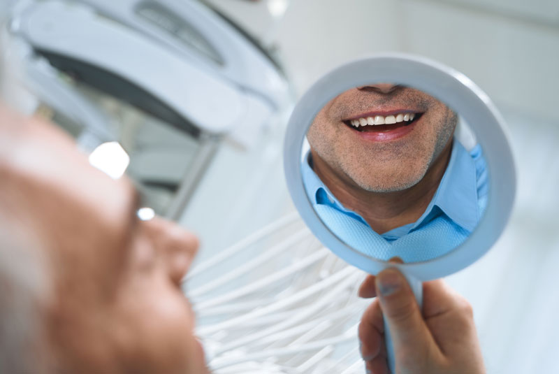 dental patient looking into mirror smiling